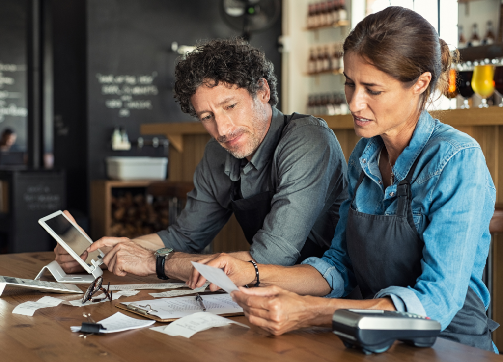 Two small business owners reviewing financial documents with the help of Quality Tax Plus Services.