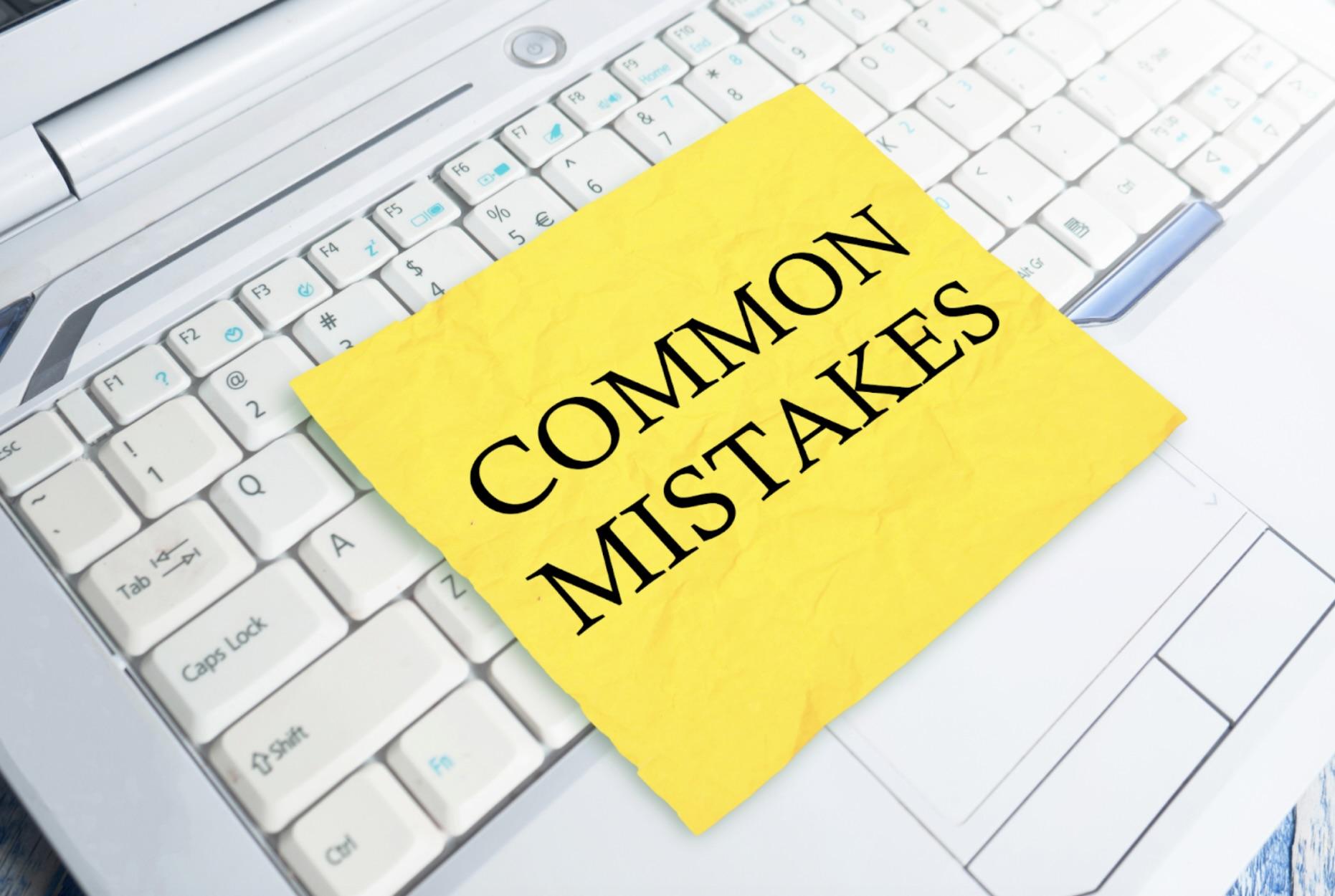 Sticky note with 'Common Mistakes' written on it placed on a keyboard, highlighting errors to avoid when dealing with tax forms.