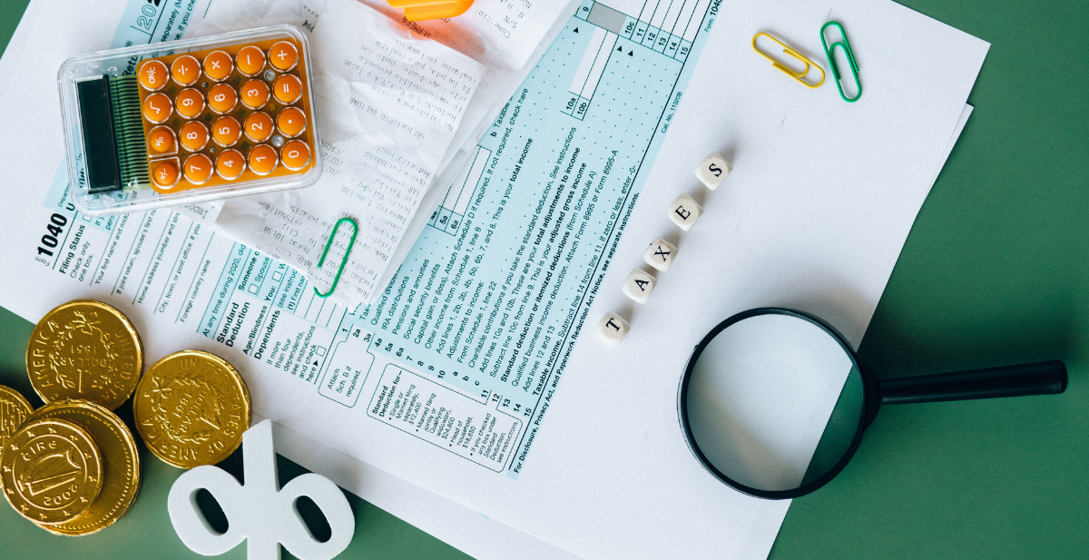 Form 1040, calculator, receipts, coins, and a magnifying glass representing tax preparation.