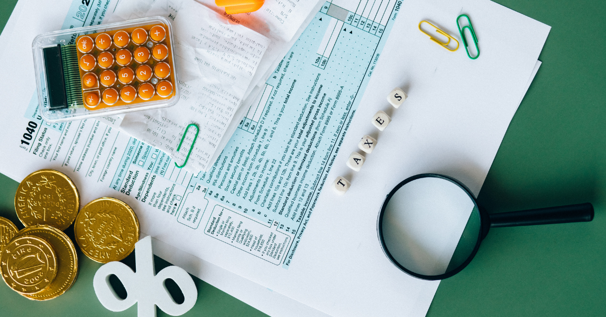 Form 1040, calculator, receipts, coins, and a magnifying glass representing tax preparation.